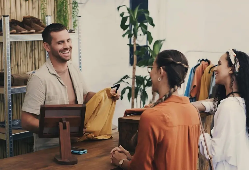 Retail store associate assisting customers at a clothing counter